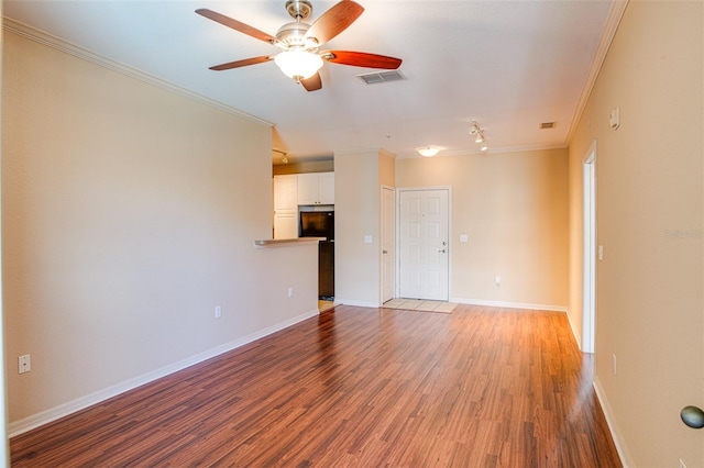 spare room featuring ornamental molding, visible vents, baseboards, and wood finished floors