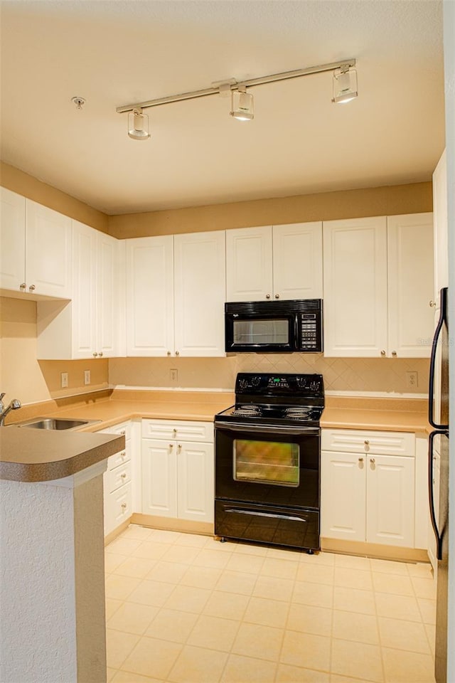 kitchen featuring a peninsula, a sink, white cabinetry, light countertops, and black appliances