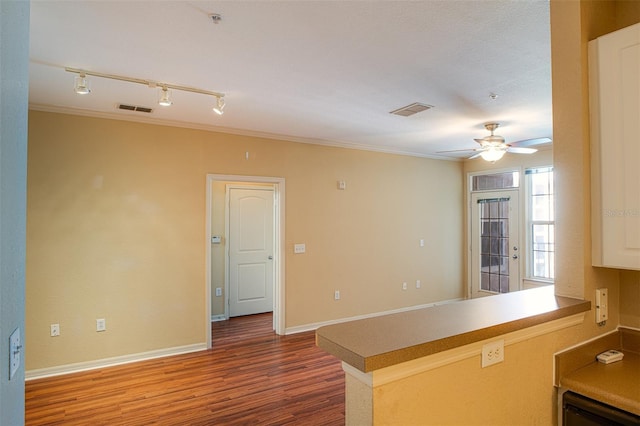 kitchen with baseboards, visible vents, a ceiling fan, wood finished floors, and a peninsula