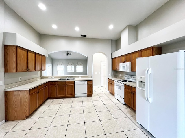 kitchen with white appliances, sink, ceiling fan, light tile patterned floors, and a towering ceiling