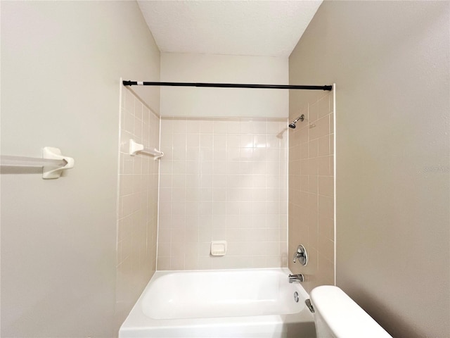 bathroom featuring tiled shower / bath combo, toilet, and a textured ceiling