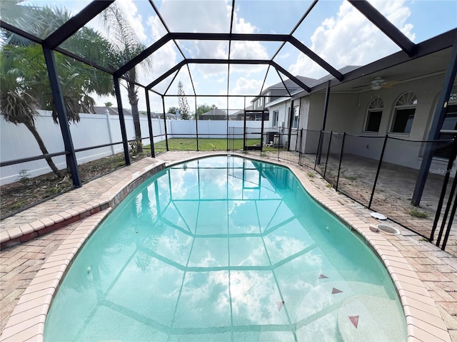 view of pool featuring a lanai, a yard, ceiling fan, and a patio area