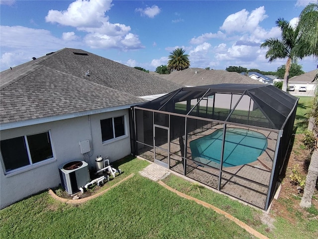 rear view of property with glass enclosure, a patio area, a yard, and central AC