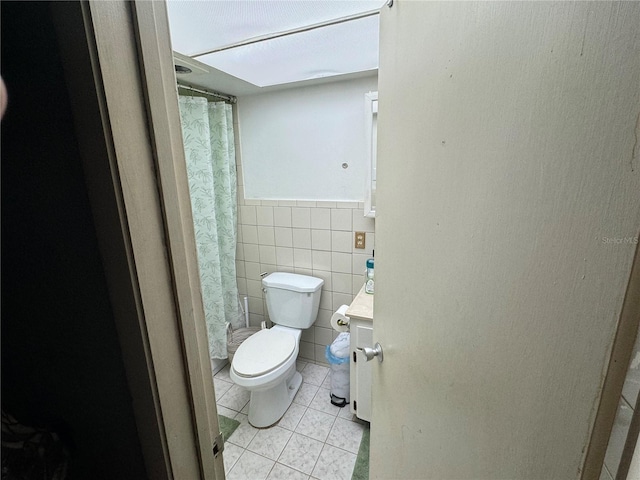 bathroom with tile patterned floors, vanity, toilet, and tile walls