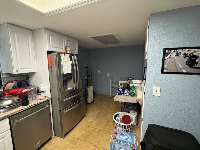 kitchen with light tile patterned flooring, white cabinets, stainless steel appliances, and ornamental molding