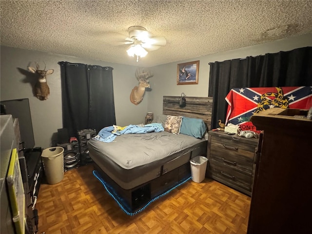 bedroom with ceiling fan, a textured ceiling, and parquet flooring