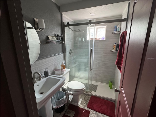 bathroom featuring a shower with door, backsplash, sink, toilet, and a textured ceiling