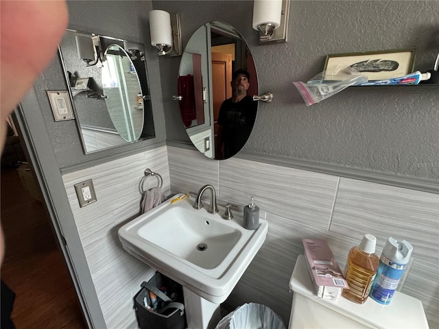 bathroom with decorative backsplash, toilet, and sink