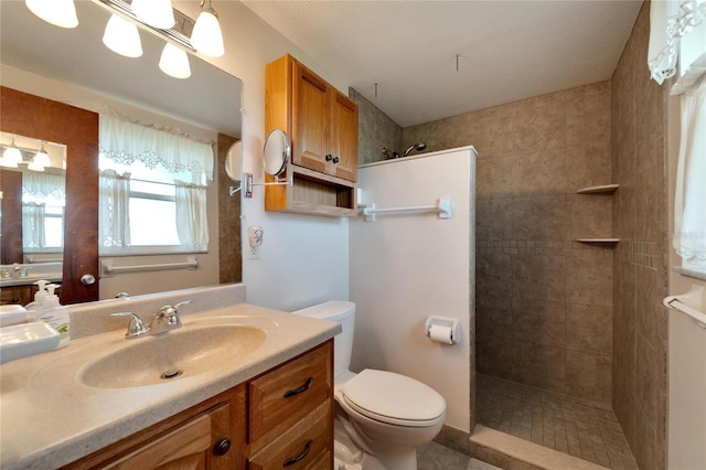 bathroom featuring a tile shower, vanity, and toilet