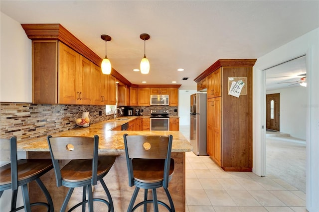 kitchen with sink, stainless steel appliances, decorative backsplash, decorative light fixtures, and kitchen peninsula