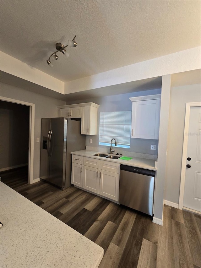 kitchen featuring sink, dark wood-type flooring, appliances with stainless steel finishes, a textured ceiling, and white cabinets