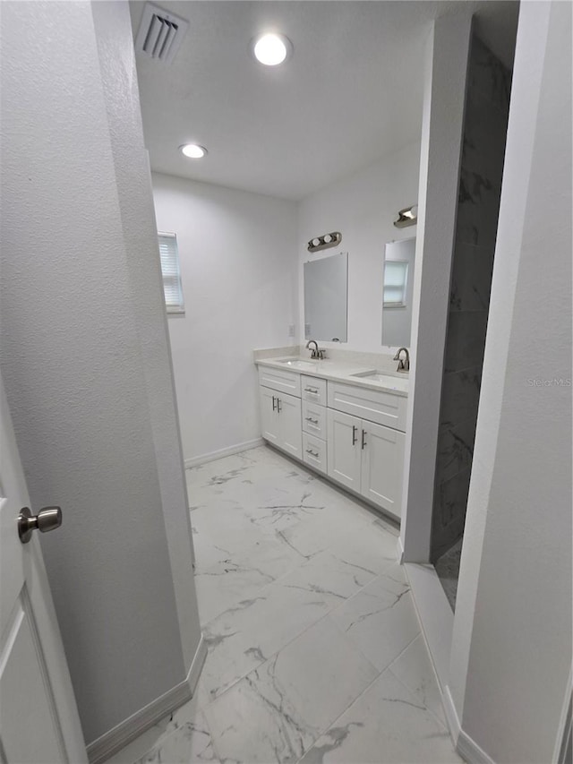 full bath featuring marble finish floor, baseboards, a sink, and double vanity