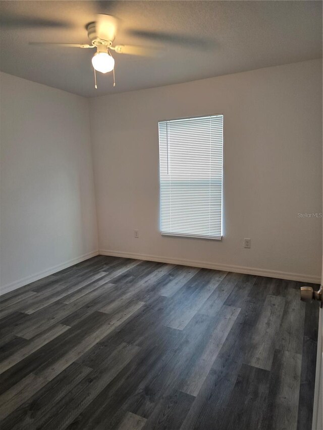 unfurnished room featuring ceiling fan, baseboards, and dark wood-style flooring