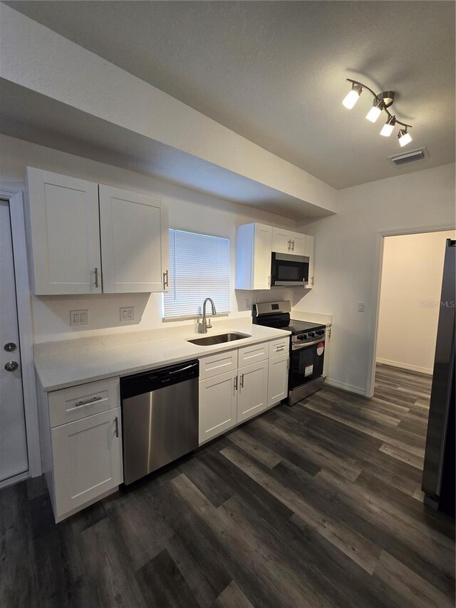 kitchen with white cabinets, stainless steel appliances, a sink, and dark wood-style flooring