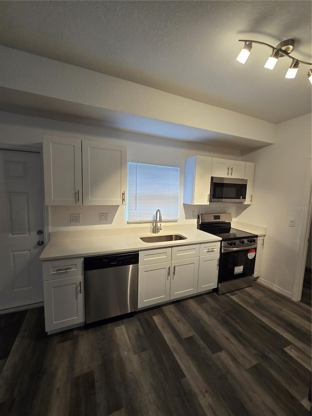 kitchen with white cabinets, a sink, dark wood finished floors, light countertops, and appliances with stainless steel finishes