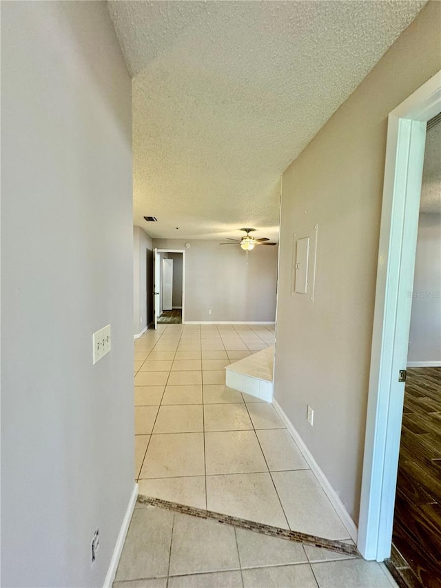 hall with light tile patterned floors and a textured ceiling