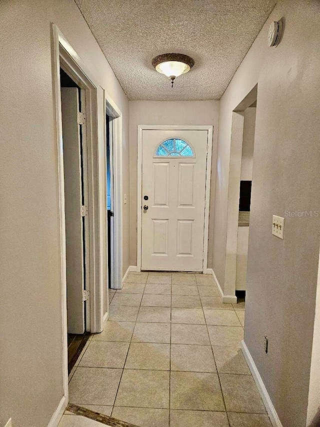 doorway to outside featuring a textured ceiling and light tile patterned floors