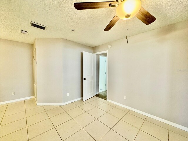 tiled spare room with a textured ceiling and ceiling fan