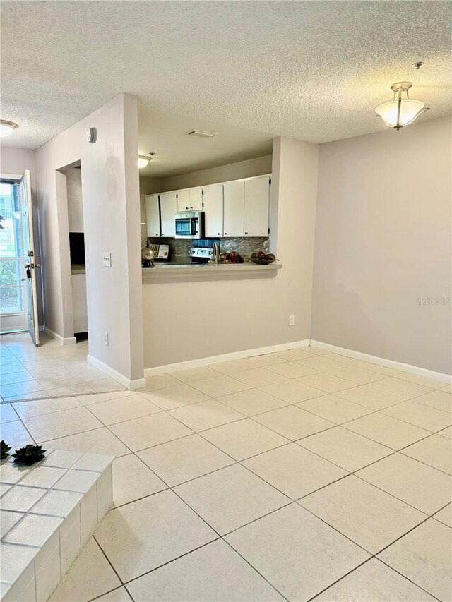 tiled empty room with a textured ceiling