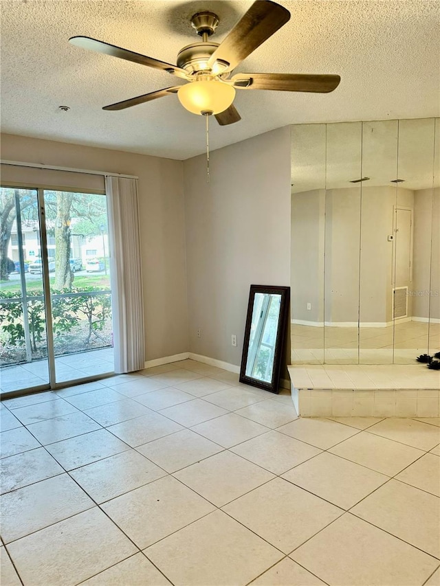 tiled spare room with ceiling fan and a textured ceiling