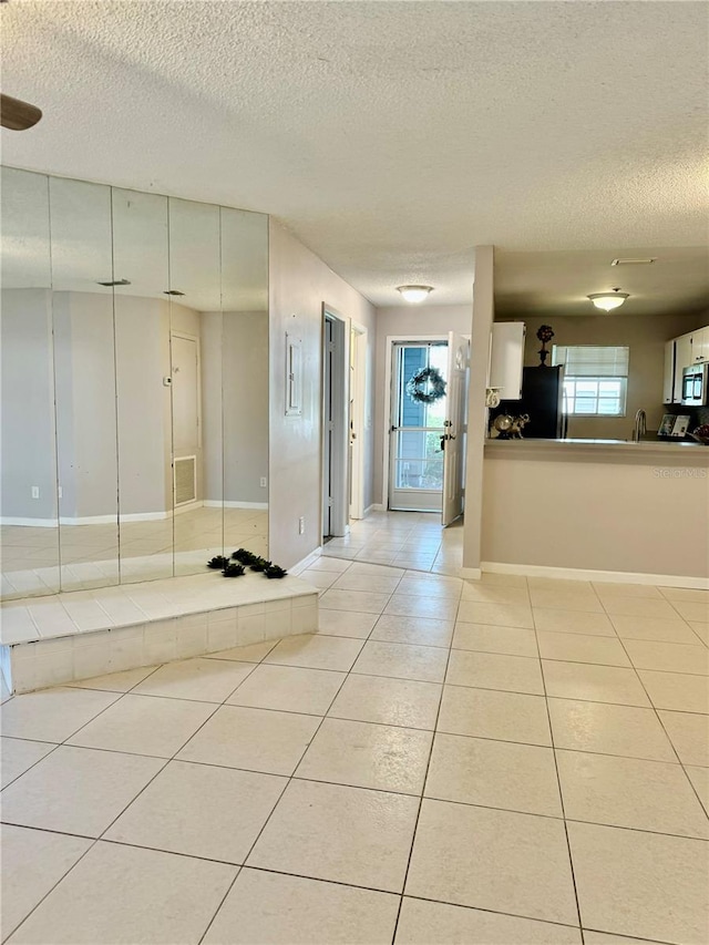 interior space with stainless steel appliances, light tile patterned floors, and a textured ceiling