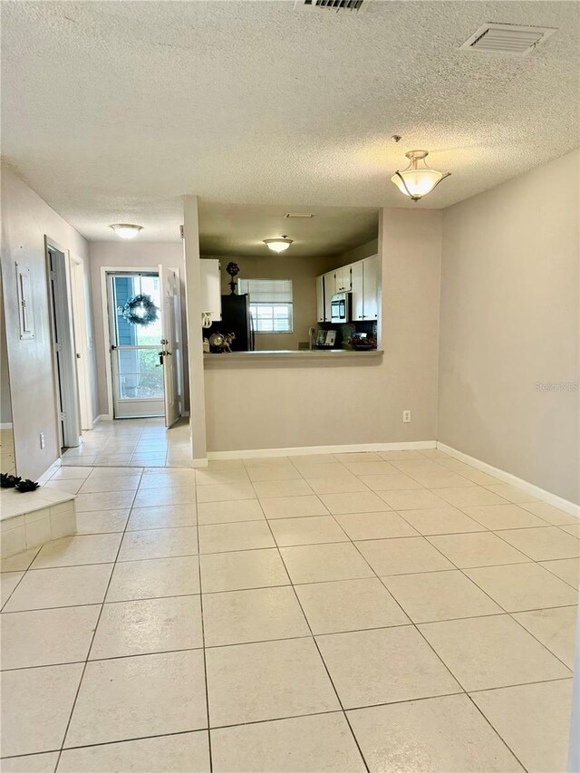 tiled empty room featuring a textured ceiling