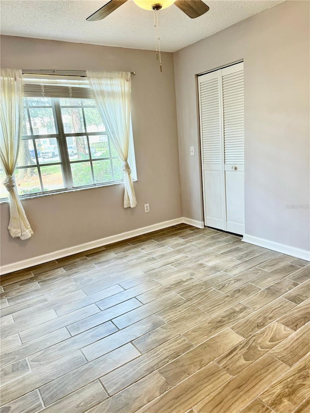 unfurnished bedroom featuring ceiling fan, a closet, light hardwood / wood-style floors, and a textured ceiling