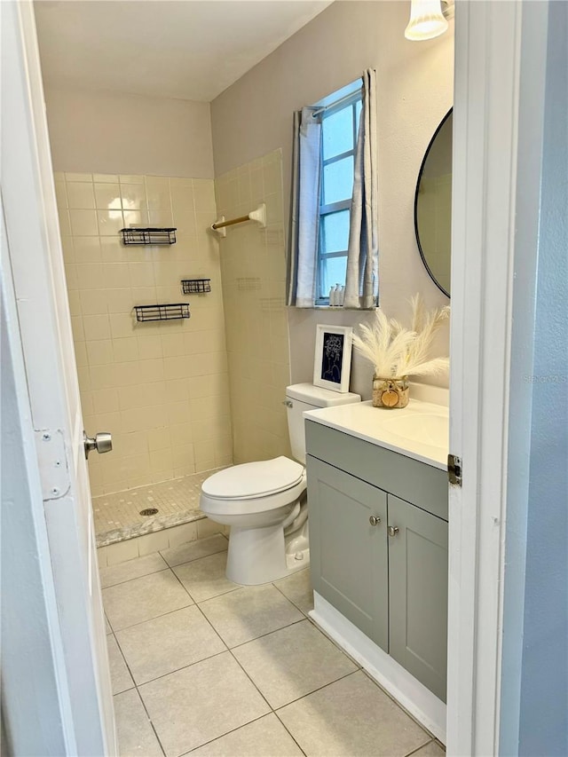 bathroom featuring a tile shower, vanity, tile patterned flooring, and toilet