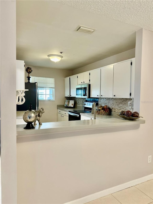 kitchen with white cabinetry, decorative backsplash, stainless steel appliances, and light tile patterned flooring