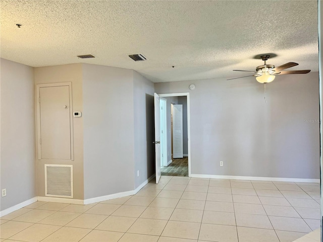 spare room featuring ceiling fan, a textured ceiling, and light tile patterned floors