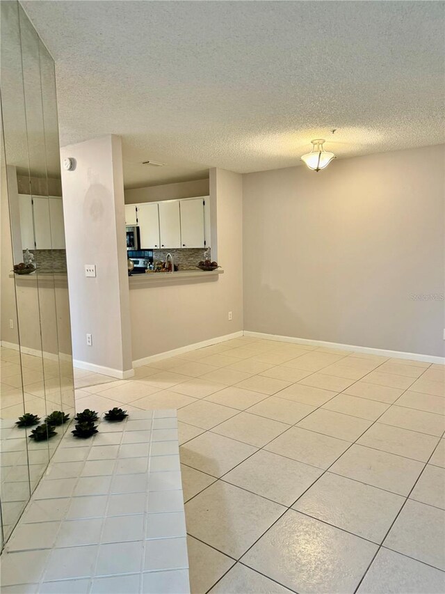 spare room featuring a textured ceiling and light tile patterned floors