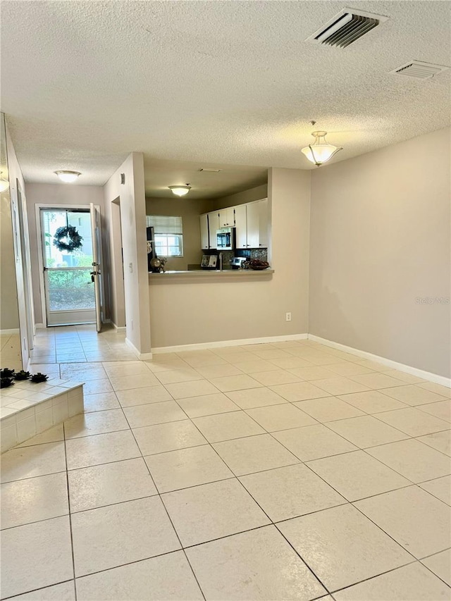 unfurnished room featuring a healthy amount of sunlight, light tile patterned floors, and a textured ceiling