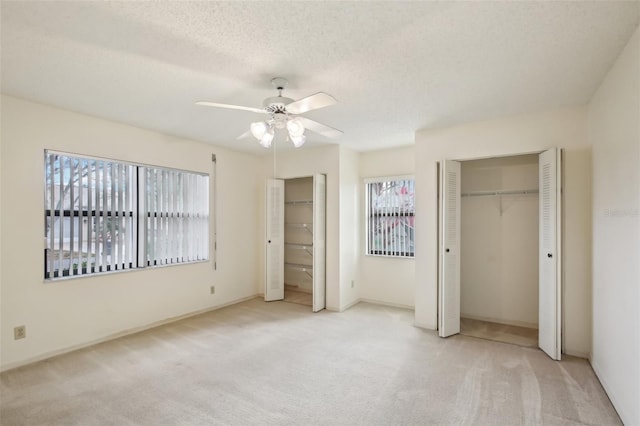 unfurnished bedroom with light colored carpet, ceiling fan, and a textured ceiling