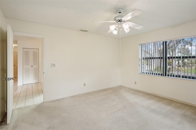 empty room with ceiling fan and light carpet