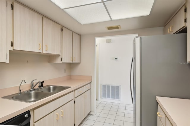 kitchen with sink, black dishwasher, light tile patterned floors, and stainless steel refrigerator