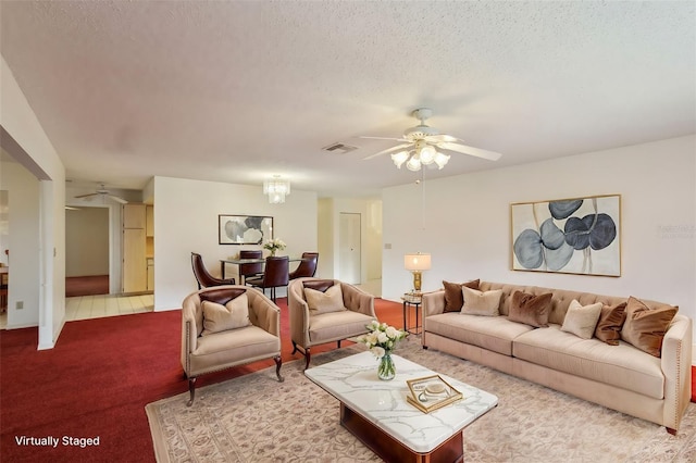 carpeted living room featuring ceiling fan with notable chandelier and a textured ceiling