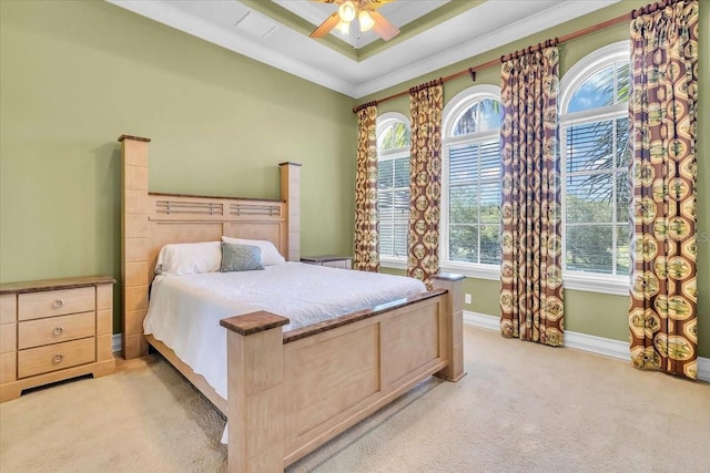 carpeted bedroom featuring a raised ceiling, ornamental molding, ceiling fan, and multiple windows