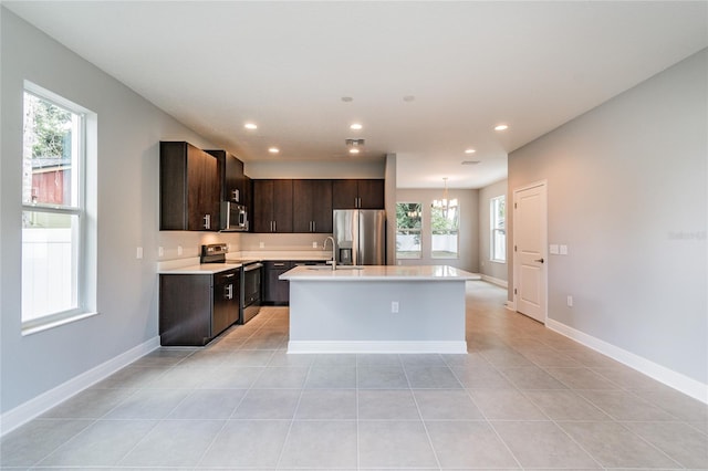 kitchen featuring a center island with sink, a wealth of natural light, dark brown cabinets, and appliances with stainless steel finishes