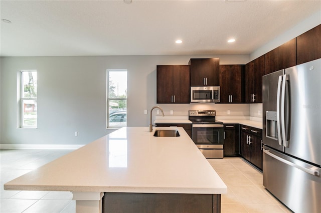 kitchen with sink, dark brown cabinetry, a kitchen island with sink, and appliances with stainless steel finishes