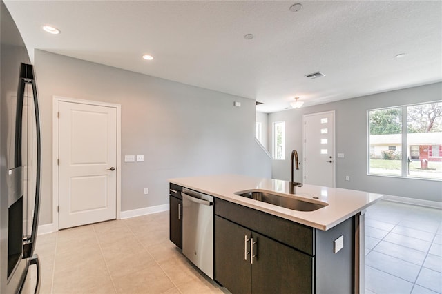 kitchen featuring sink, fridge, an island with sink, stainless steel dishwasher, and a healthy amount of sunlight