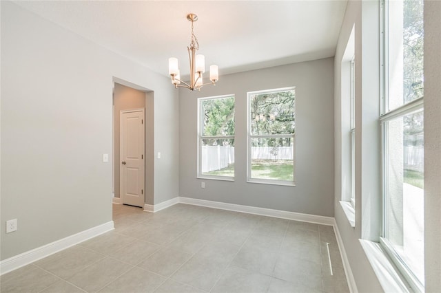 spare room with light tile patterned floors, a chandelier, and plenty of natural light