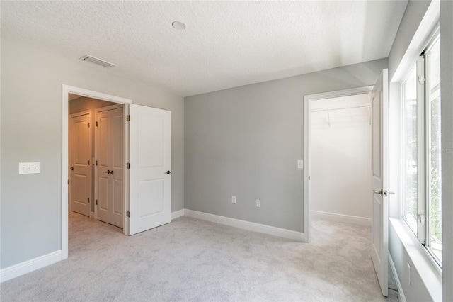 unfurnished bedroom with a textured ceiling, a closet, and light carpet