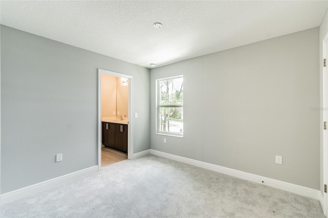 unfurnished bedroom with light carpet and connected bathroom