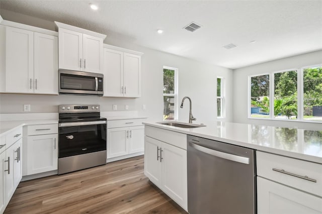 2909 W Spruce St, Tampa, FL 33607 - kitchen with appliances with stainless steel finishes, light countertops, recessed lighting, light wood-style flooring, and white cabinets