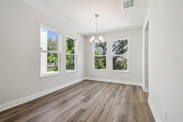 2909 W Spruce St, Tampa, FL 33607 - spare room with healthy amount of natural light, a chandelier, wood finished floors, and a textured ceiling
