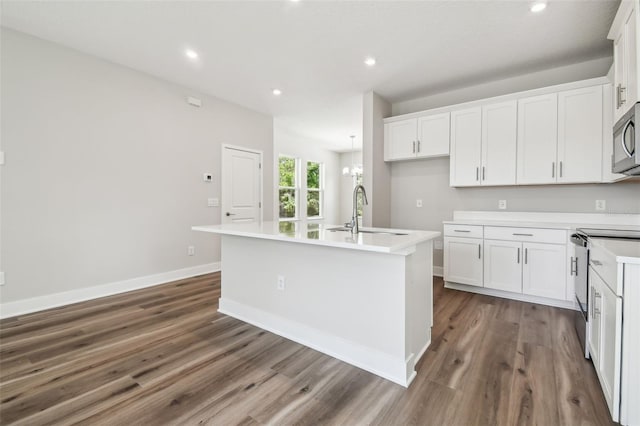 2909 W Spruce St, Tampa, FL 33607 - kitchen featuring stainless steel appliances, white cabinetry, an island with sink, wood finished floors, and recessed lighting
