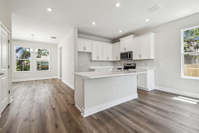 2909 W Spruce St, Tampa, FL 33607 - kitchen featuring stainless steel microwave, wood finished floors, light countertops, plenty of natural light, and recessed lighting