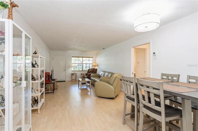 dining area with light wood-type flooring and a textured ceiling