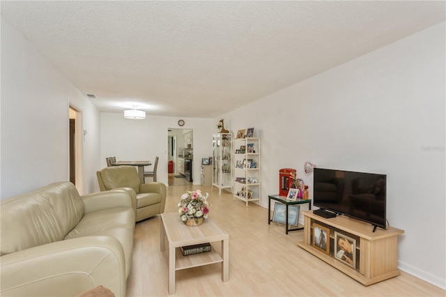 living room featuring light wood-style floors, visible vents, and a textured ceiling