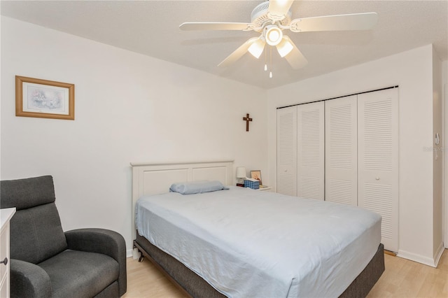 bedroom with light wood-style floors, a closet, ceiling fan, and baseboards